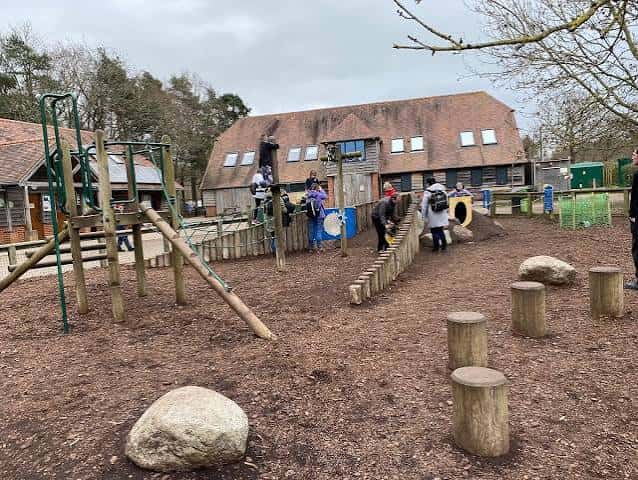 Área de juegos infantil con niños jugando y edificio de fondo
