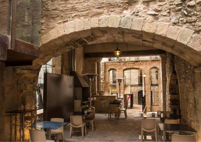 Vista del patio interior con arcos de piedra y mesas dispuestas para eventos