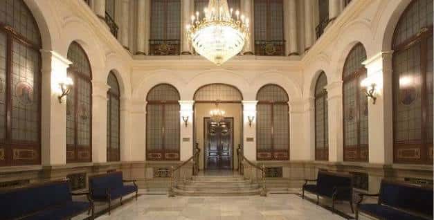 Hall de entrada con arcos, escalera y gran candelabro