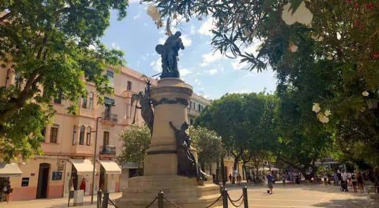 Vista del monumento central en Passeig de Vara de Rey con edificios coloridos al fondo