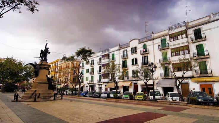 Passeig de Vara de Rey con fachadas blancas y balcones bajo cielo nublado