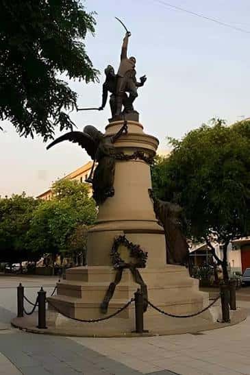 Detalle del monumento ecuestre en el paseo con árboles y atardecer