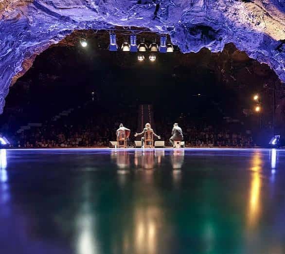 Concierto en el escenario principal con iluminación dramática y el techo de lava volcánica