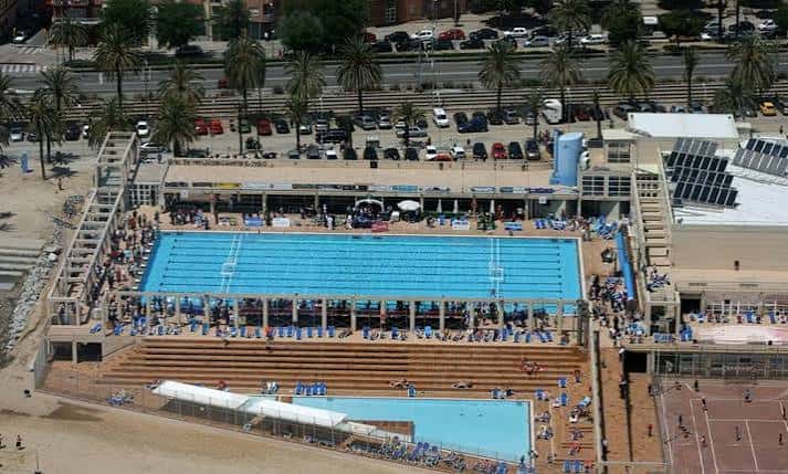 Vista aérea del complejo deportivo con piscina principal, gradas y zona de playa