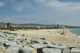 Platja del Varador desde un ángulo elevado, mostrando la arena y el rompeolas de piedra
