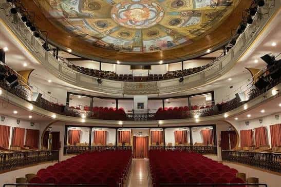 Interior del auditorio con butacas rojas, balcones y techo decorado