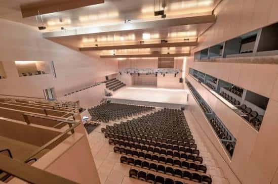 Interior del auditorio con gradas, escenario y sistema de iluminación profesional