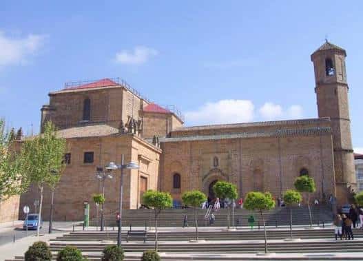 Fachada principal de la Basílica con escalinata y árboles ornamentales en primer plano