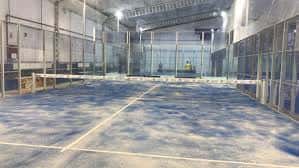 Pista de pádel vacía con iluminación artificial y superficie azul
