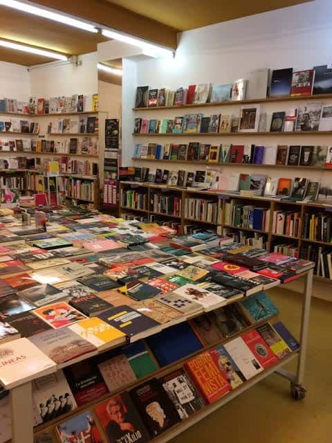 Interior de la librería con mesas de libros y estanterías llenas