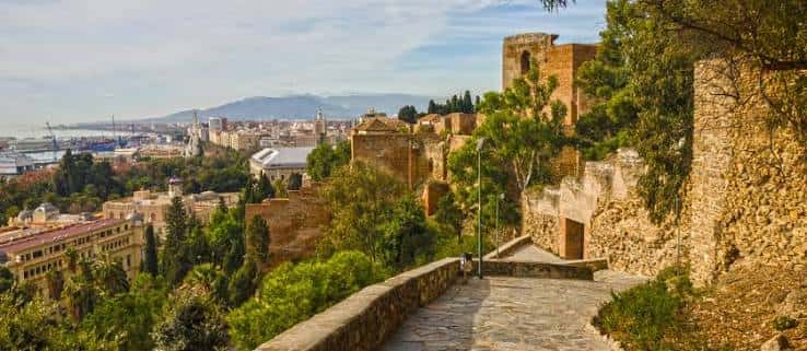 Camino empedrado entre las ruinas del castillo con paisaje urbano y marino