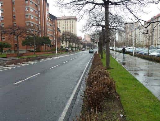 Avenida con árboles y edificios de viviendas en un día lluvioso
