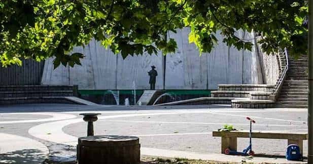 Plaza de Salvador de Madariaga con fuente y estatua bajo árboles