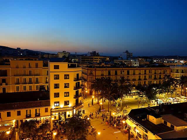 Vista nocturna de la plaza iluminada con ambiente festivo