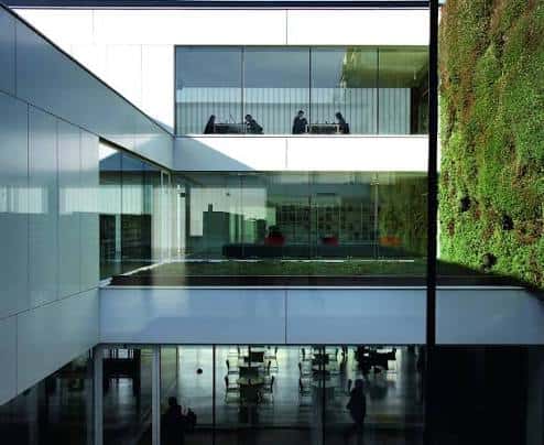 Vista del atrio interior con paredes de vidrio y jardín vertical