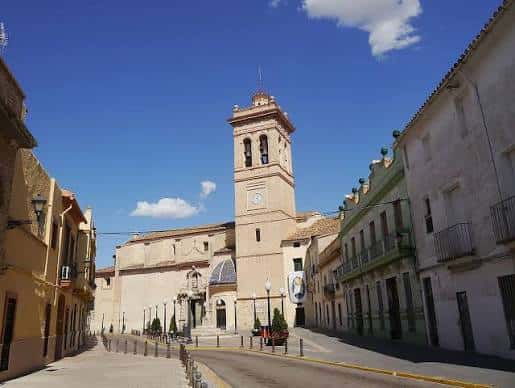 Vista panorámica de la Plaza de la Iglesia en Torrent con la fachada de la Iglesia de la Asunción bajo un cielo azul despejado