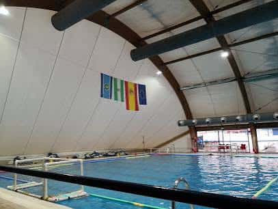 Piscina cubierta del complejo con banderas colgantes y estructura de techo arqueado