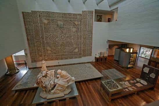 Interior del Museo de Zamora con mosaicos romanos expuestos y esculturas en vitrinas bajo iluminación natural