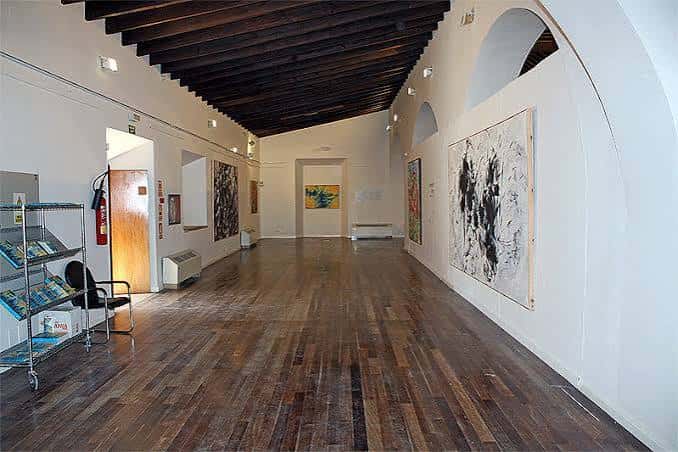 Galería interior con arte y techumbre de madera