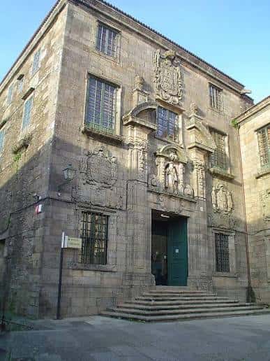 Fachada histórica del edificio con detalles arquitectónicos en piedra y entrada principal