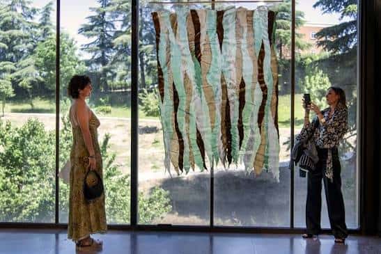 Interior del museo con obra textil y visitantes observando