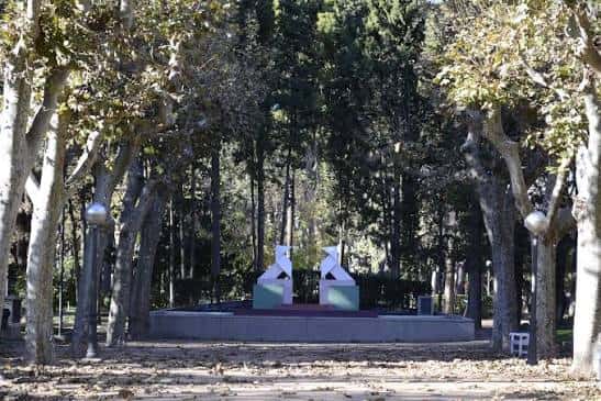 Vista del parque con árboles y esculturas blancas en el centro