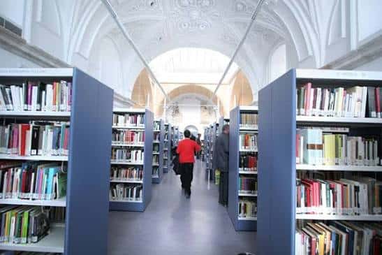 Pasillo interior de la biblioteca con estanterías y bóvedas decoradas