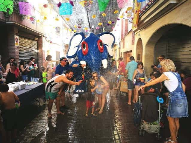 Fiesta popular en el carrer de Sant Jaume con un elefante de agua y gente disfrutando