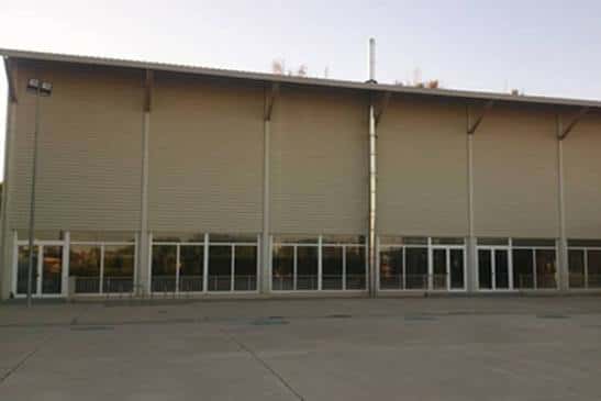 Vista exterior del pabellón deportivo con grandes ventanales y fachada moderna