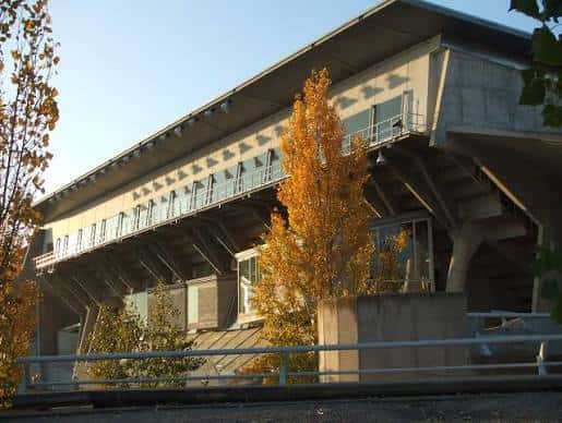 Vista exterior del Palacio Municipal de Deportes de Huesca con fachada de hormigón y árboles otoñales