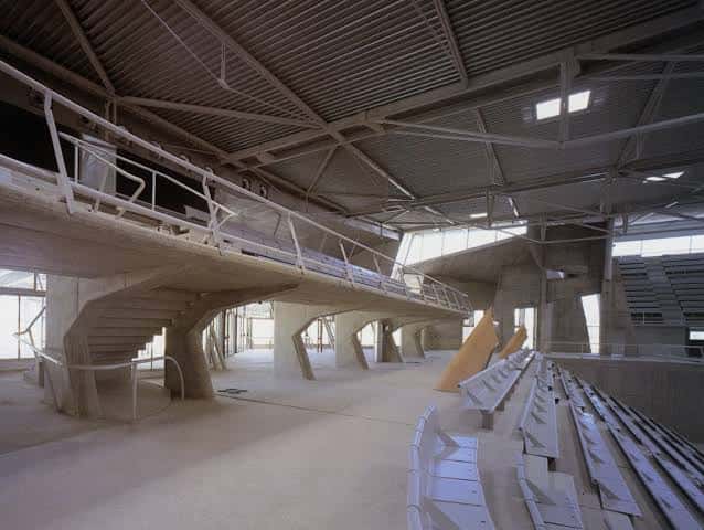 Interior del pabellón mostrando gradas, escaleras y estructura arquitectónica de hormigón