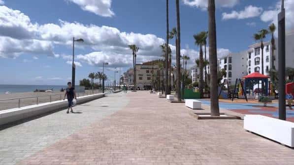 Paseo peatonal con palmeras y zona de juegos infantiles junto a la playa