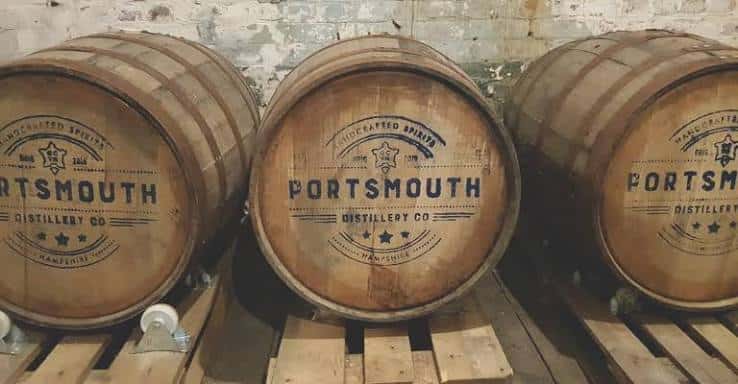 Barricas de roble con el logo de Portsmouth Distillery en un almacén
