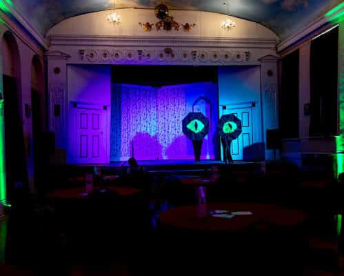 Interior del auditorio del Groundlings Theatre con iluminación de escenario y mesas de evento