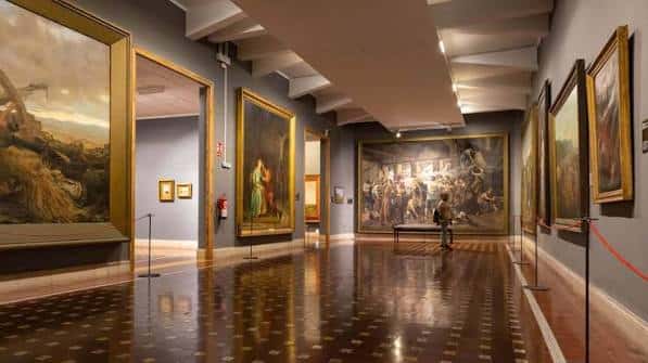 Sala de exposiciones con grandes lienzos y suelo de madera pulida