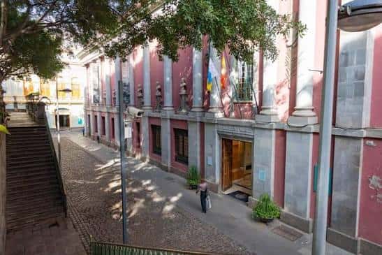 Vista exterior del edificio desde la calle con escaleras y árboles