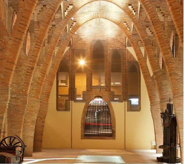 Interior del Celler Modernista mostrando arcos de ladrillo y ventana central con reja