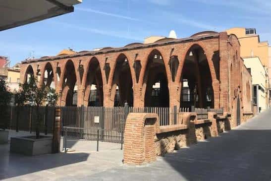 Fachada exterior del Celler Modernista con arcos de ladrillo y entorno urbano