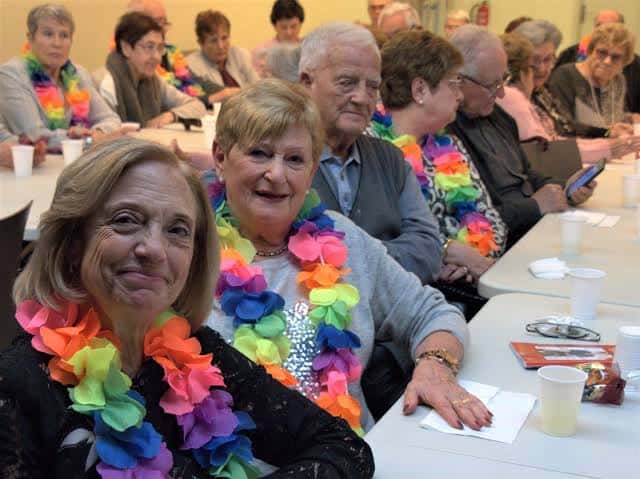 Grupo de residentes mayores celebrando en el interior del centro con guirnaldas coloridas