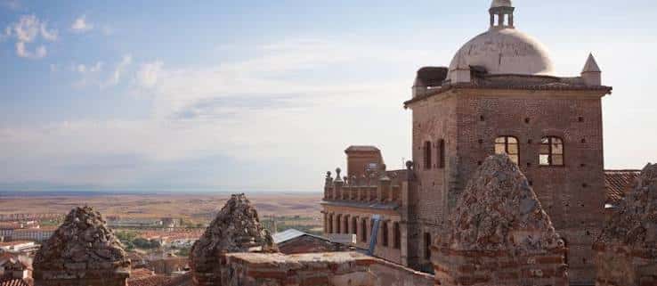 Ángulo elevado del palacio mostrando la torre y el paisaje de Cáceres al fondo