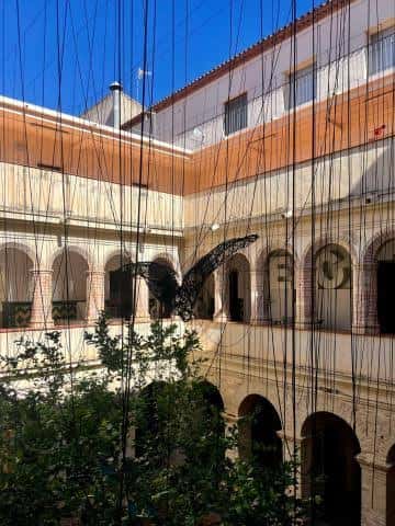 Vista del patio interior del Centre d'Art i Cultura con arcos y una escultura colgante