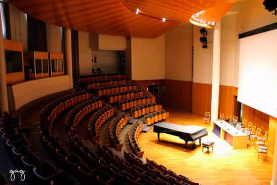 Escenario con piano y proyector, ideal para eventos culturales