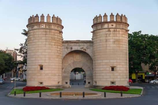 Puerta de Palmas en Badajoz durante el atardecer con jardines y tráfico alrededor