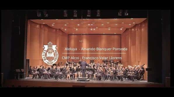 Interior del auditorio durante un concierto con orquesta y pantalla de proyección