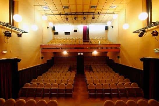 Interior del auditorio con butacas amarillas, balcón y sistema de iluminación profesional