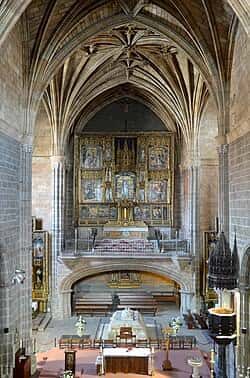 Interior de la iglesia con retablo mayor dorado y bóvedas de crucería