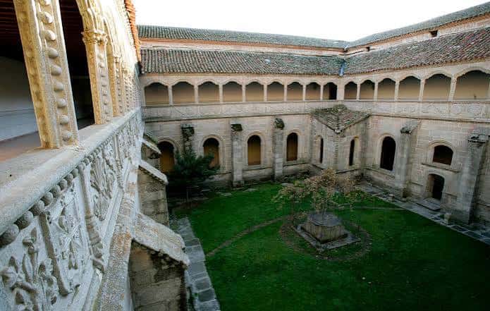 Claustro del monasterio con patio central, arquerías y detalles ornamentales en piedra