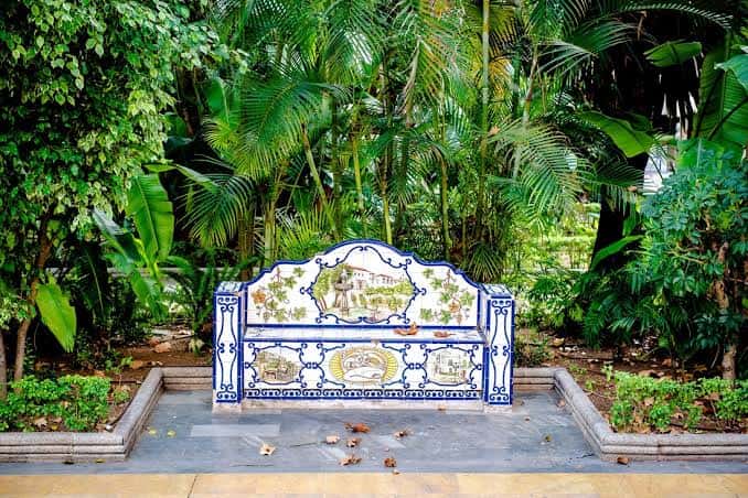 Banco de azulejos tradicionales andaluces en un rincón verde del parque