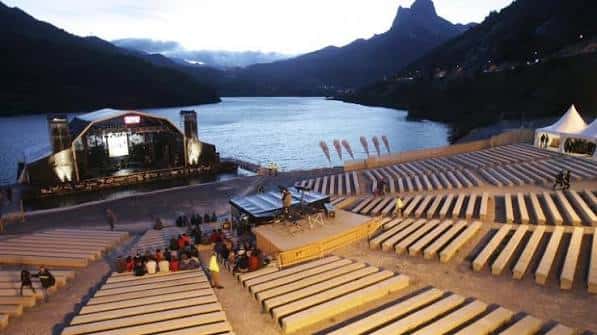 Atardecer en el Auditorio Natural de Lanuza con el escenario iluminado y el lago de fondo