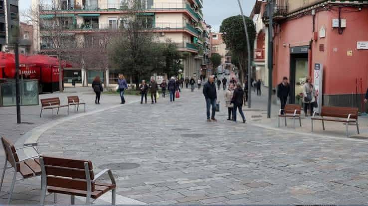 Vista general de la zona peatonal de Quatre Cantons con bancos y personas caminando